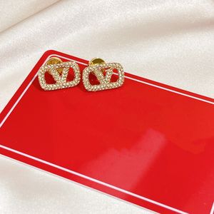 Designer di orecchini disegnano lettere per donne, gioielli per orecchini in oro alla moda e d'atmosfera, gioielli per feste, scatole regalo per gioielli da sposa
