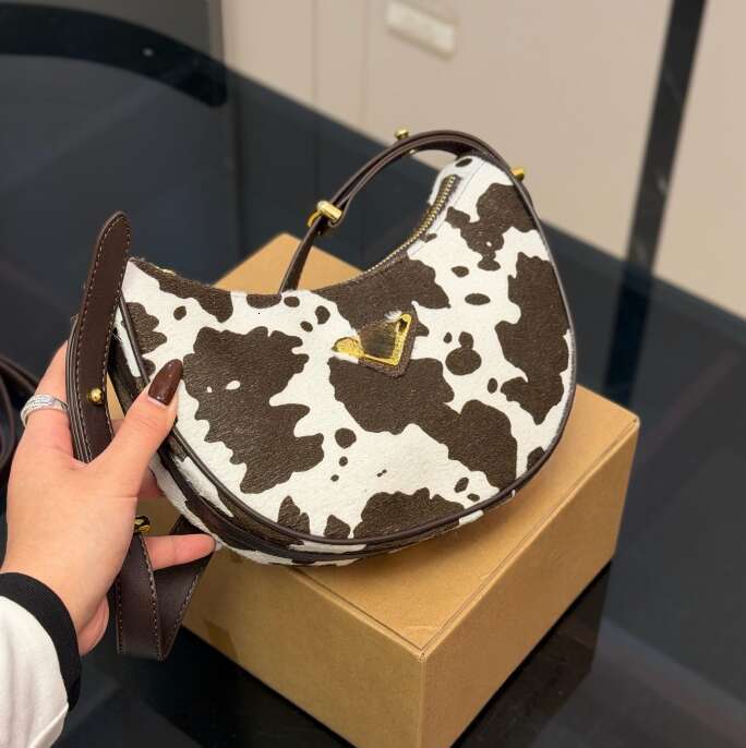 The creamy fluffy cow print clashes with retro crescent shaped bags Sweet and edgy vibe Various styles of handbags eye catching gold tipped crossbody bags tote bags