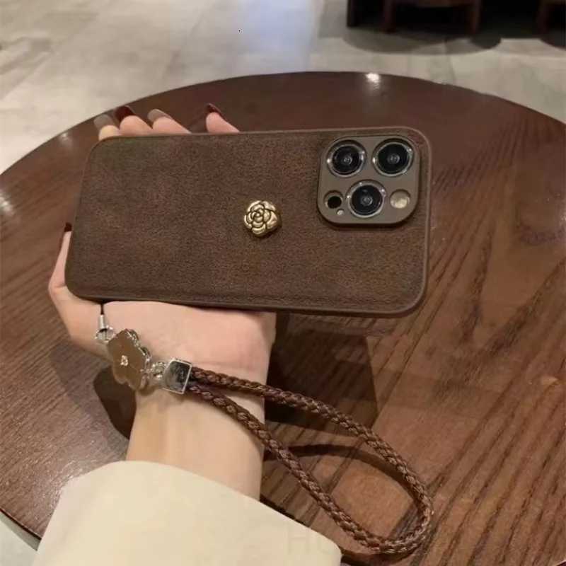 Luxury Suede Leather Metal Camellia Phone Case with Braided Wrist Strap For iPhone 17 Air 16 15 14 Plus 13 Pro Max 12 11 | Premium Skin-Feel Back Cove