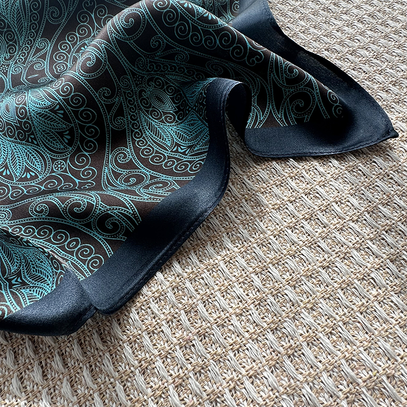A genuine silk scarf in the green totem style, suitable for women to wear. It offers a fashionable and elegant neck support function. It is a small-si