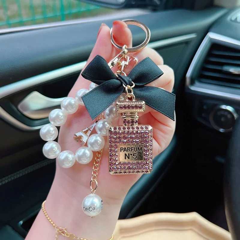 Keychains Lanyards Alloy diamond inlaid bow shaped perfume bottle key chain creative pearl chain pendant bag exit key chain J241010