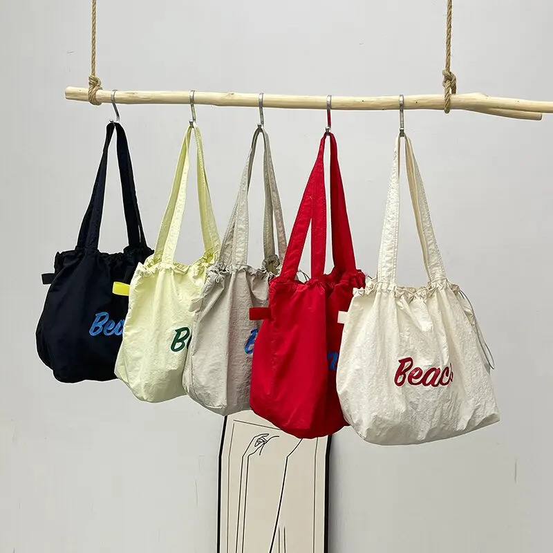 Womens Korean version letter printed canvas shoulder bag casual version commuting drawstring large capacity bag 241008