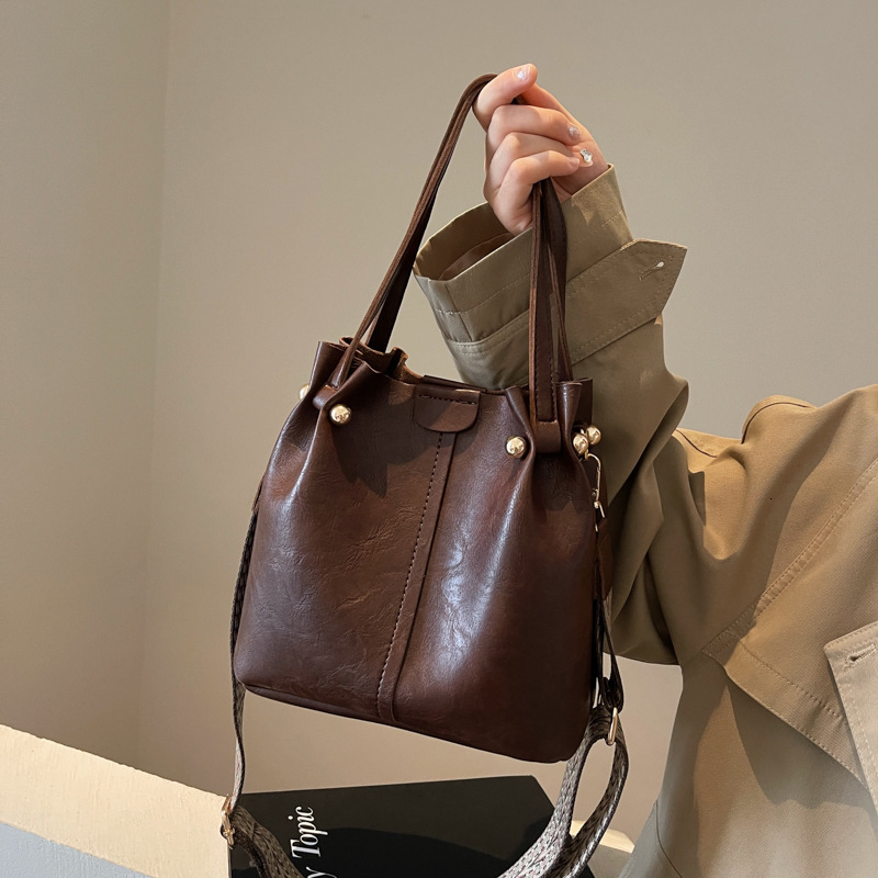 New autumn retro fashion simple texture bucket bag shoulder width design women s shoulder bag commuting bag autumn new designer bag women s crossbody 