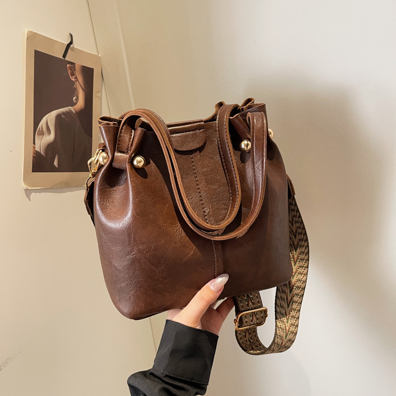 New autumn retro fashion simple texture bucket bag shoulder width design women s shoulder bag commuting bag autumn new designer bag women s crossbody 