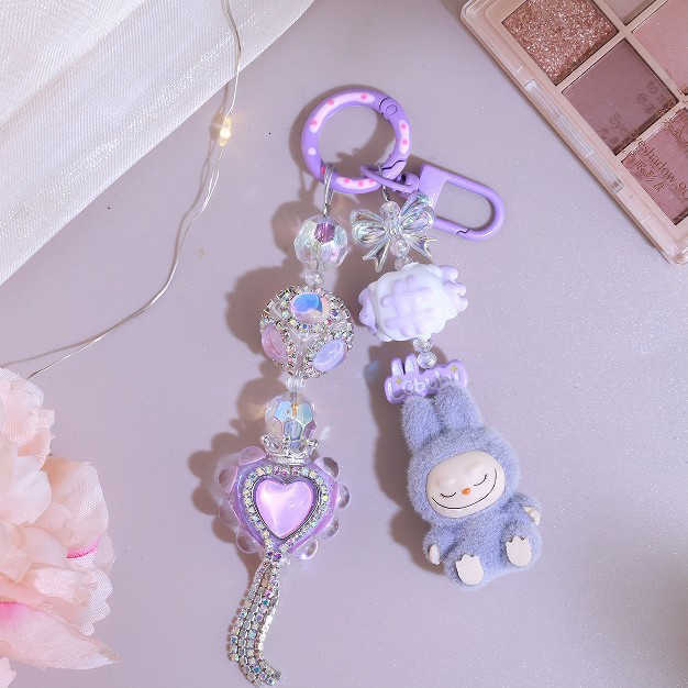 Adorable kid DIY makes a kid backpack with a keychain, a chain for hanging keys, a pendant for a girlfriend's phone, an alloy item with cute bead