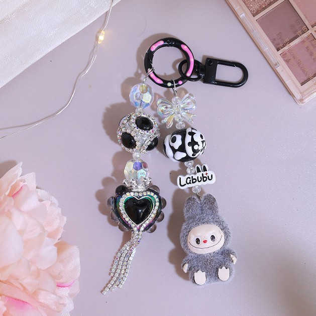 Adorable kid DIY makes a kid backpack with a keychain, a chain for hanging keys, a pendant for a girlfriend's phone, an alloy item with cute bead