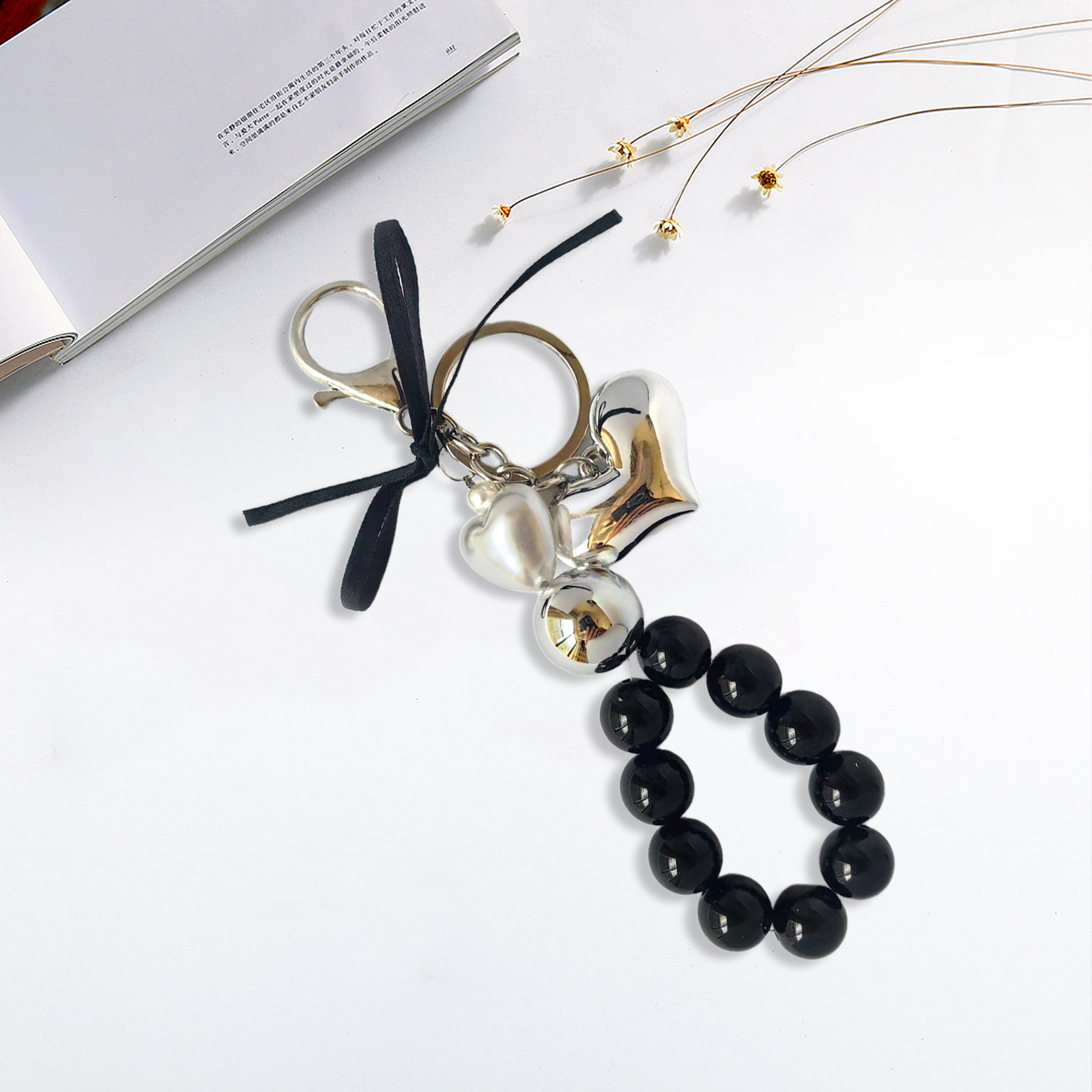 Fashion-forward phone charm, metal heart design, metallic pearls, black pearl strand, trendy accessory, anti-loss feature, easy to carry