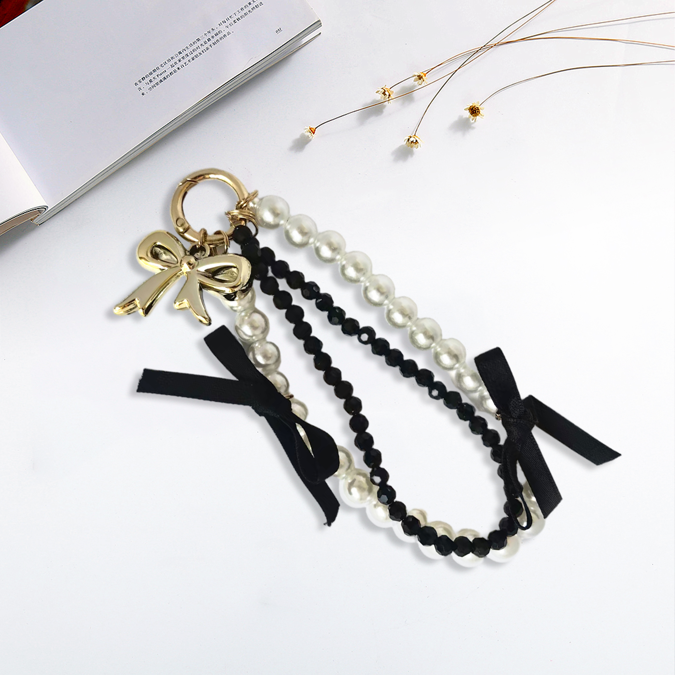 White pearl bracelet, black diamond bracelet, gold bow, black ribbon bow phone strap. Stylish pairing, creative design, anti-loss, easy to grab.