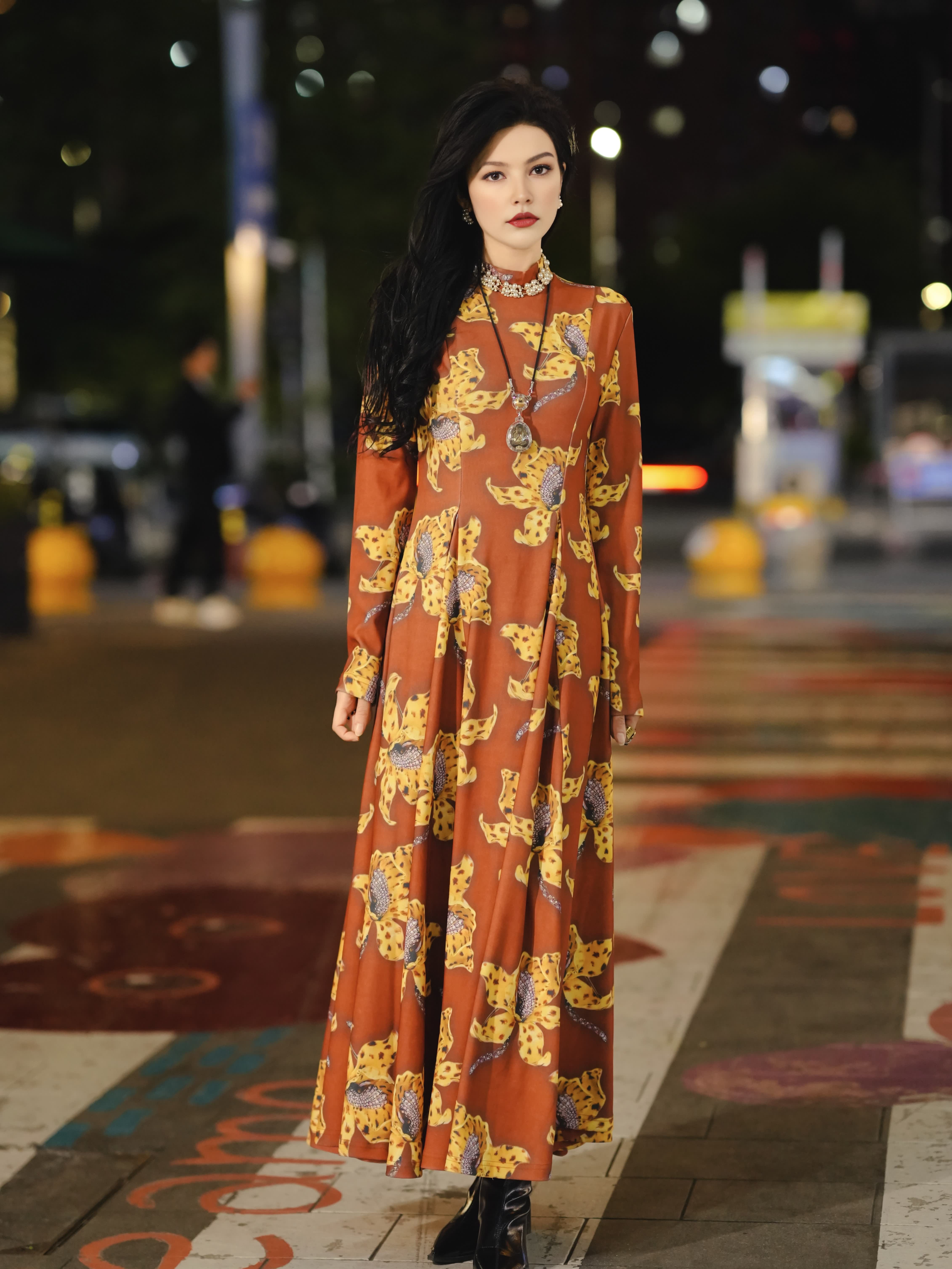 New designer dress features a brown color with a yellow floral print, long sleeves, and a flattering, fitted silhouette; it exudes elegance and a touc