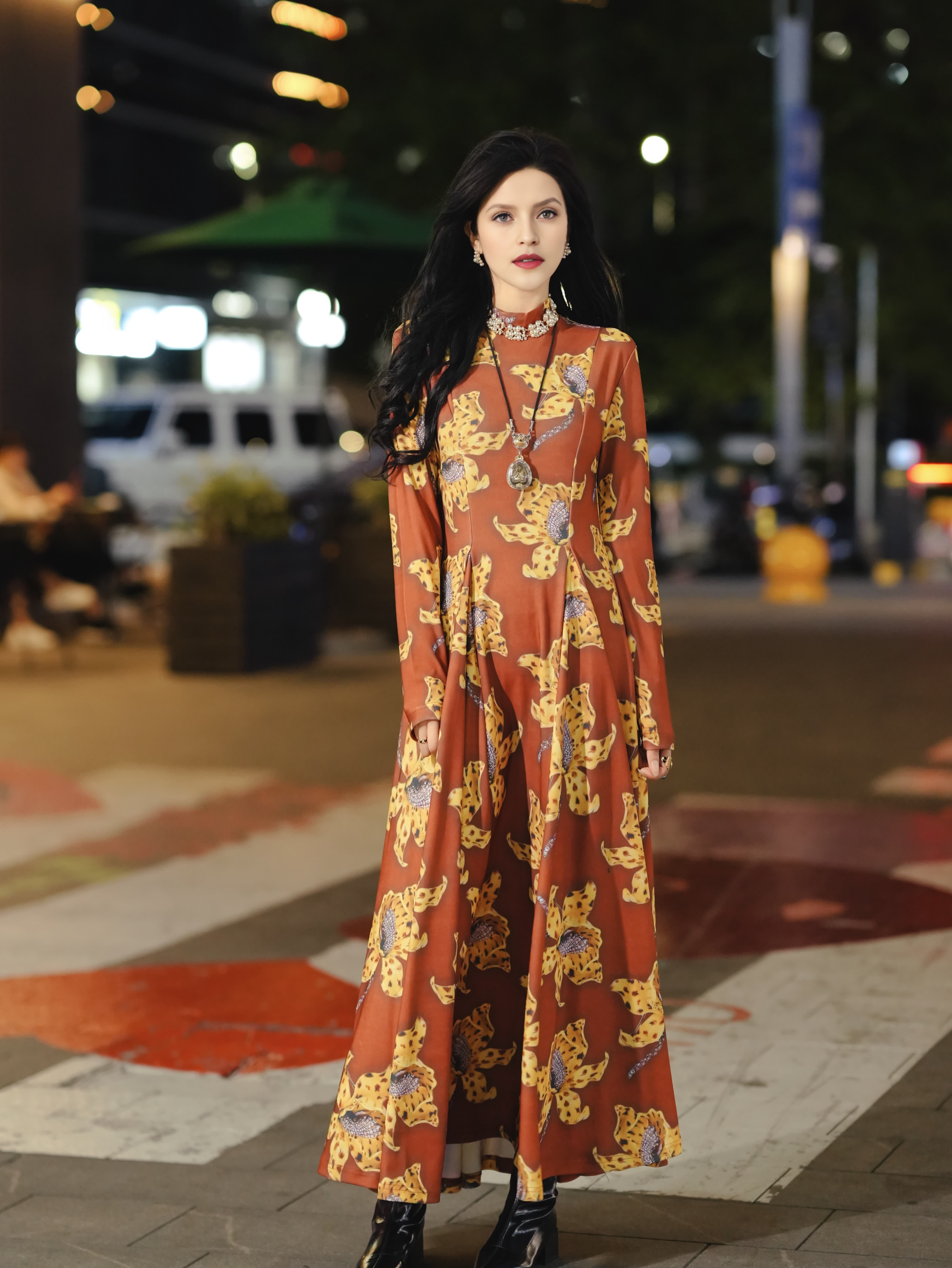 New designer dress features a brown color with a yellow floral print, long sleeves, and a flattering, fitted silhouette; it exudes elegance and a touc