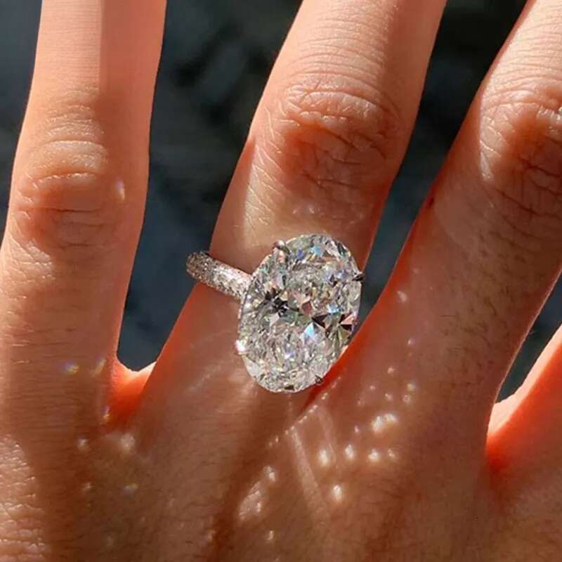 3. A 14K white gold ring weighing 4 grams, featuring oval moissanite gemstones set in diamonds. It is a men's wedding ring, with a classic and fa