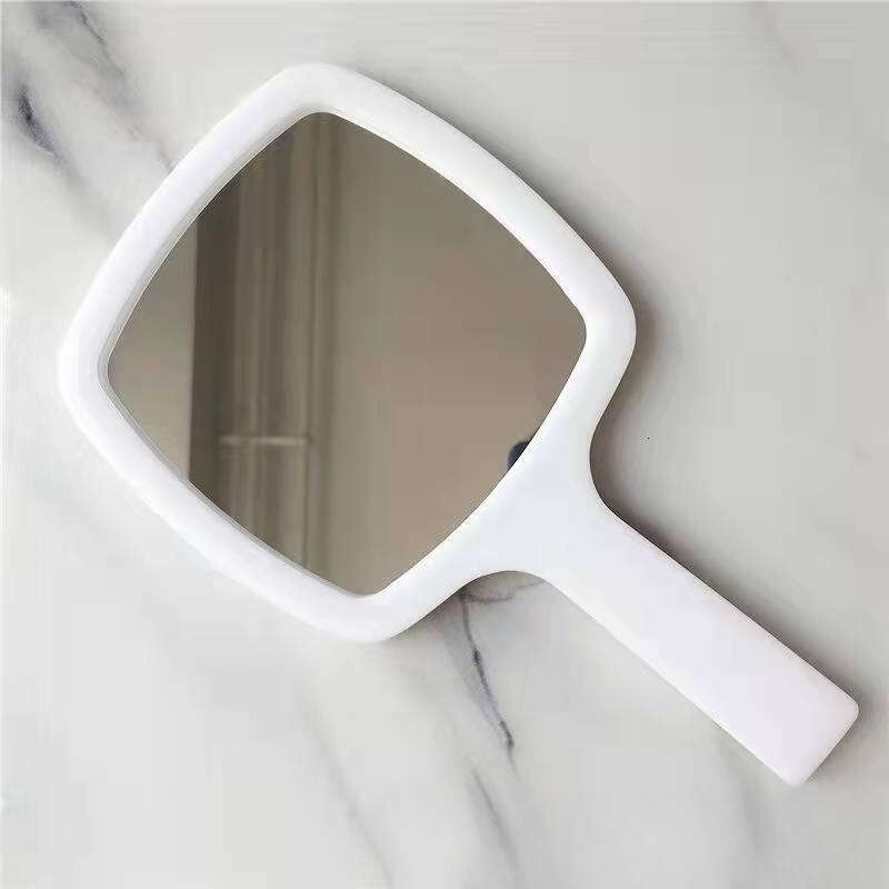 Designer holding black and white classic style women's travel portable small mirror essential makeup