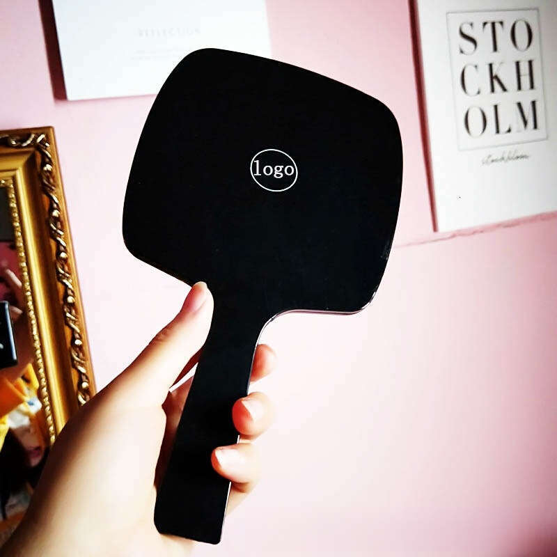 Designer holding black and white classic style women's travel portable small mirror essential makeup