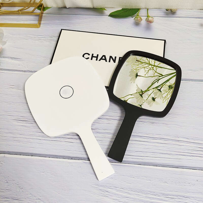Designer holding black and white classic style women's travel portable small mirror essential makeup