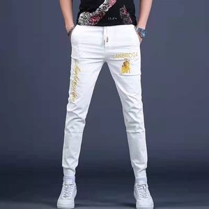 Trendy White Men's Jeans 2022 Verano Nuevos pantalones transpirables Logotipo de la marca Diseño de bordado Hot Diamond Sequin Jeans Pie pequeño Elástico Slim Lace Up