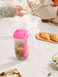 1 taza de ensalada de plástico rosa con recipiente para aderezo de ensalada y tenedor.