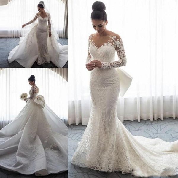 2019 Diseñador Mangas largas Sirena Vestidos de novia Cuello transparente Ilusión Apliques de encaje Arco Faldas con botones Volver Capilla Tren Vestidos de novia