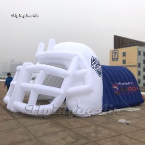 Il grande giocatore di sport gonfiabile del casco di football americano attraversa il tunnel dell'entrata con il logo per gli eventi della partita