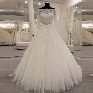 Abiti da sposa sbalorditivi a-line Collo a barchetta trasparente Applicazioni di pizzo con perline Maniche illusionate Abiti da sposa in tulle punteggiato con fascia in cristalli