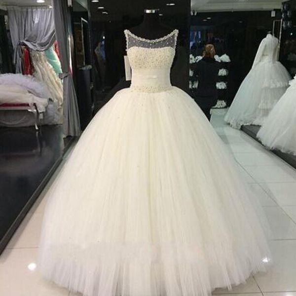 Perle squisite Cristalli Abiti da sposa impreziositi da ballo Collo trasparente Senza maniche Vita increspata Abiti da sposa in tulle gonfi Lunghezza del pavimento