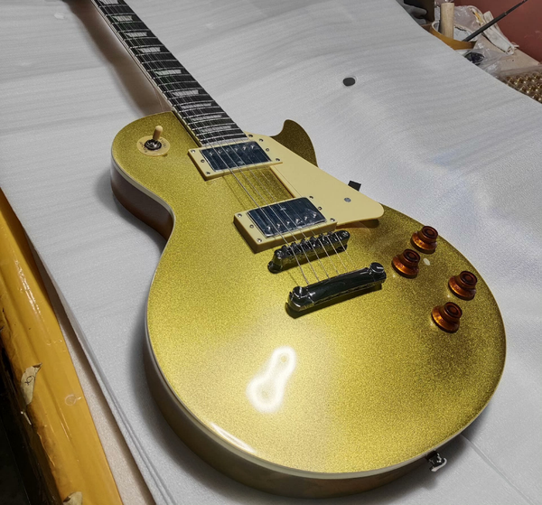 

Striking Gold Glitter Single-Cut Electric Guitar: Cream Pickguard, Metal-Frame Humbuckers, Tune-O-Matic Bridge