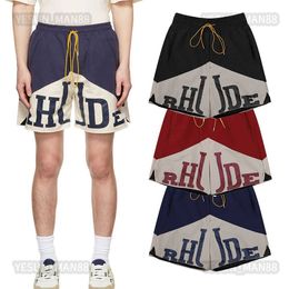 American Fashion Rhudes Panel de contraste de color Impreso para hombre y para mujer Pantalones cortos de baloncesto con cordón elástico Pantalones cortos de cinco puntos de malla informal