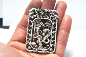 Serpent argenté double face en cuivre blanc antique jouant au bambou. Le collier a été hissé en pendentif.