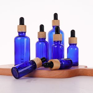 Bouteilles de parfum de sérum d'huile essentielle en verre bleu avec le chapeau de grain en bois de compte-gouttes pour le cosmétique liquide 5ml 10ml 30ml 50ml 100ml