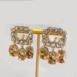 Boucles d'oreilles de luxe avec pendentif en cristal tridimensionnel jaune vif. Strass scintillants, arêtes logo plaquées or. Boucles d'oreilles créateurs, bijoux créateurs Prestige