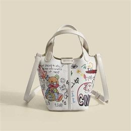 Bolsos de hombro elegantes Nuevas mujeres bolso de diseñador lindo versátil pequeño oso graffiti cubo simple cesta de verduras portátil moño al vapor madre crossbody 230323