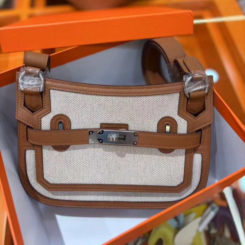 Designer off-white canvas with brown leather trim, classic twist lock fastening and adjustable shoulder strap combining style with practicality