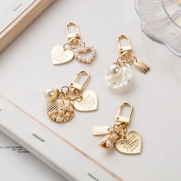 Llavero con colgante de concha de corazón, accesorios para auriculares, recuerdo de fiesta, etiqueta de letra elegante a la moda, llavero con colgante de perlas de imitación