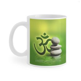 Mokken om symbool met zenstenen op zachte groene koffiekopjes melkthee mok aum pranava meditatie ohm boeddisme