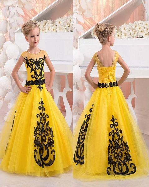 Nuevos vestidos amarillos para desfile de niñas Cuello joya Mangas cortas Apliques de encaje negro Longitud del piso de tul Fiesta de cumpleaños de niña de flores D5026686