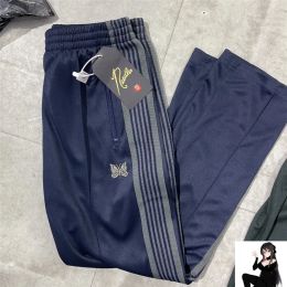 Pantalones Y2K BOOTCUT Agujas Pantalones de chándal Hombres Mujeres Alta calidad Poli Agujas lisas Pantalones Logotipo de mariposa Pantalones de rayas moradas de punto