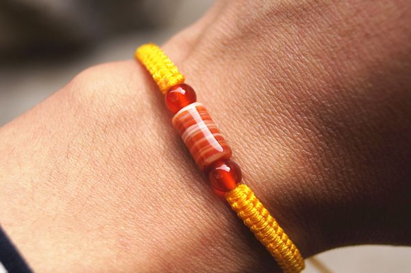 Le bracelet porte-bonheur noeud plat jaune + perles cylindriques de sardonyx