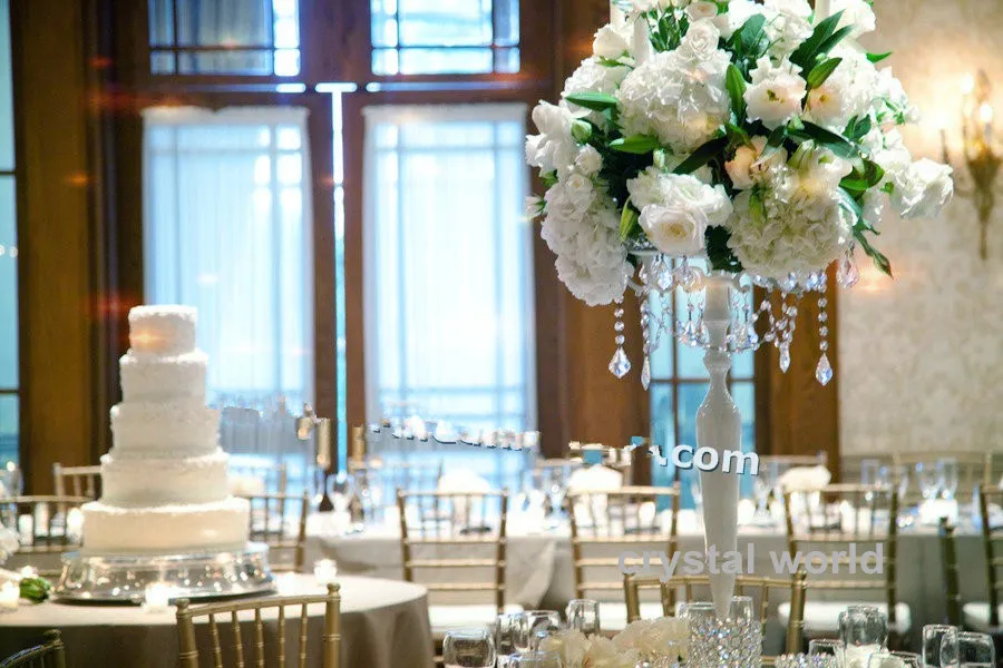 クリスタルのぶら下がっているテーブルの中心部の白い結婚式の燭台