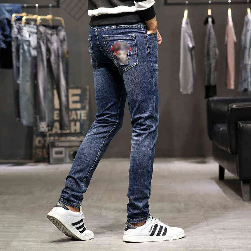 Portret mannen geborduurde jeans herenmode casual broek slanke pasvorm kleine voeten slijtage Koreaanse versie