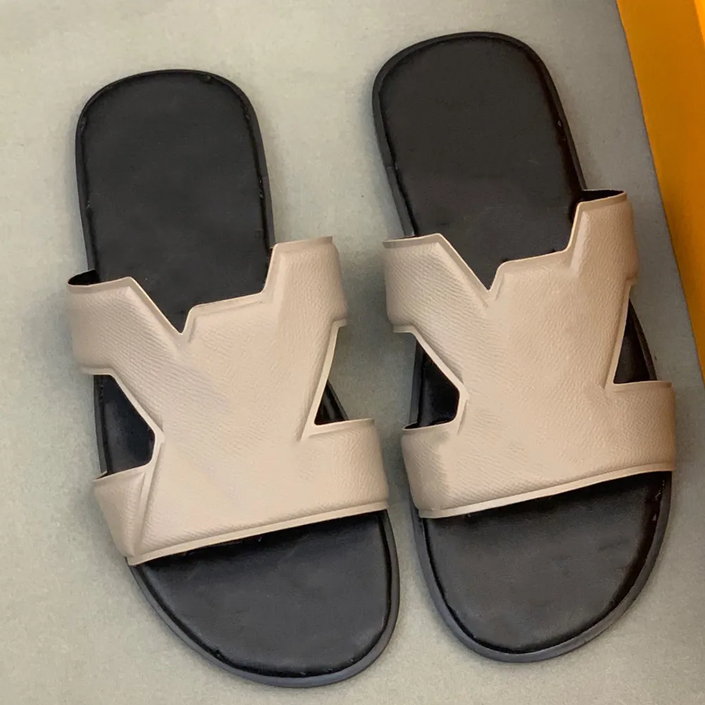 les sandales sont confectionnées à partir de cuir grainé souple avec un graphisme de la marque entrelacé sur le dessus de la chaussure et une semelle intérieure en cuir confortable de la marque.
