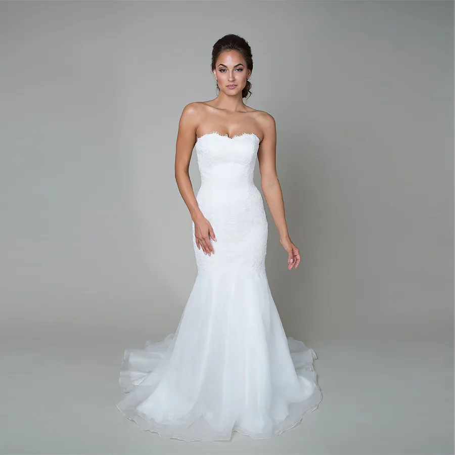 O vestido de casamento do estilo de trompete possui uma cintura caída um decote querido uma saia de organza fluindo e o vestido nupcial do laço amarelado