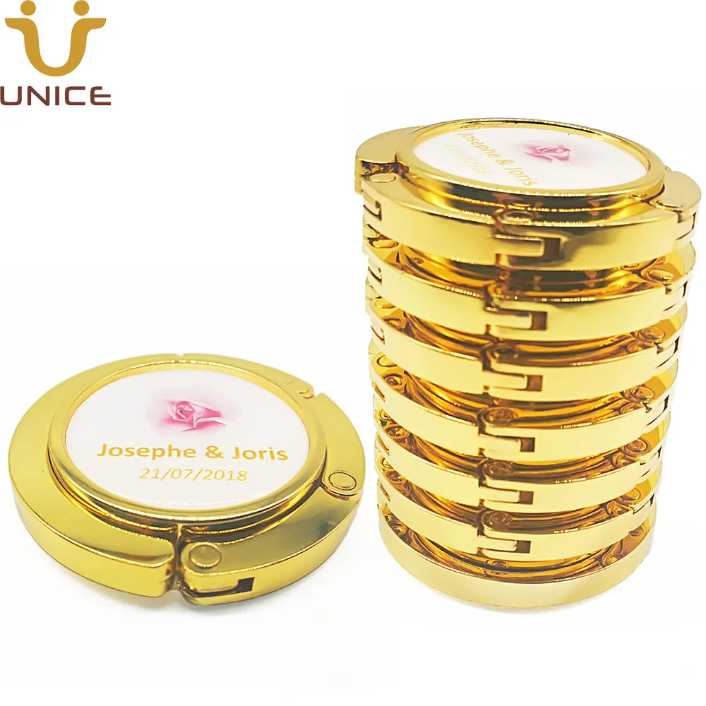 MOQ 100 PCS Logotipo personalizado Percha de bolsa dorada sin espejo Color dorado Monedero plegable magnético Gancho Mesa Bolso Titular Regalo de boda de belleza