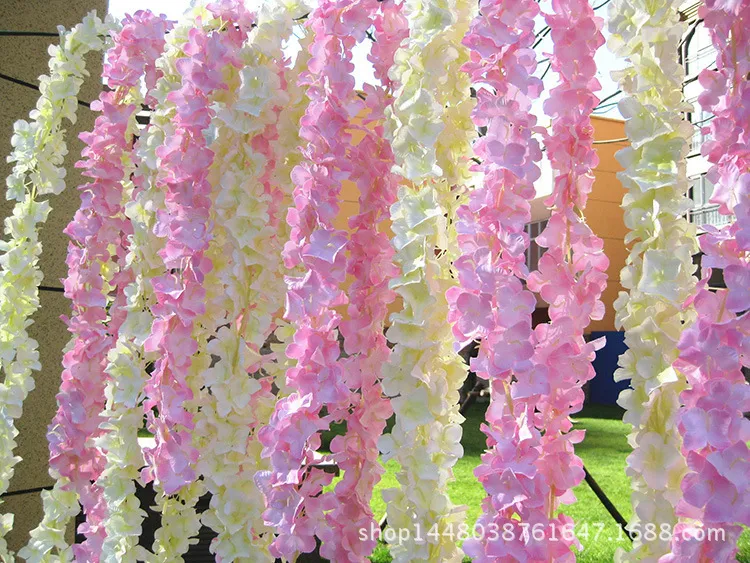 造花藤の藤の花の弦の結婚式の花の壁の背景の装飾家のぶら下がっているアクセサリー偽の花ガーランド