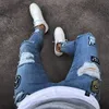 Songsangding Badge Mäns Jeans Trend Knee Hole Hole Zipper Feet Pants Hole Explosion Mäns Denim Trousers