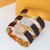 Europa America Fashion Style Uomo Donna Donna Acciaio al titanio Oro 18 carati Inciso V Iniziali Avvolgere Bracciale rigido in pelle nera / marrone 3 colori