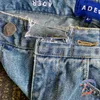 Hombres Jeans Mujeres Adererror Bordado de alta calidad Borlas Cintura asimétrica Pantalones dañados Tendencia Pantalones sueltos salvajes