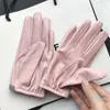 Kurze Damen-Schaffellhandschuhe aus echtem Leder. Rosafarbener Motorradhandschuh im Schleifendesign