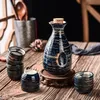 Japansk skulluppsättning Asiatisk restaurang Drinkware med en keramisk tokkuri -flaska och 4 Ochoko koppar borstade jordnära cirkel på blå glasyr