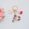 Kvinnor Populär Lila Blomma Guldfolieharts Initial Letter Keychain Med Tassel