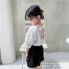Корейский стиль летние дети девушки 2 шт. Устанавливает белые кружева V-образным вырезом рубашки + черные тыквенные шорты детская одежда E8032 210610