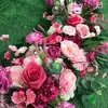 ピンクのバラの赤の造花の眺望の付いた結婚式の看板テーブルランナーの花輪の背景花輪花の配置の装飾